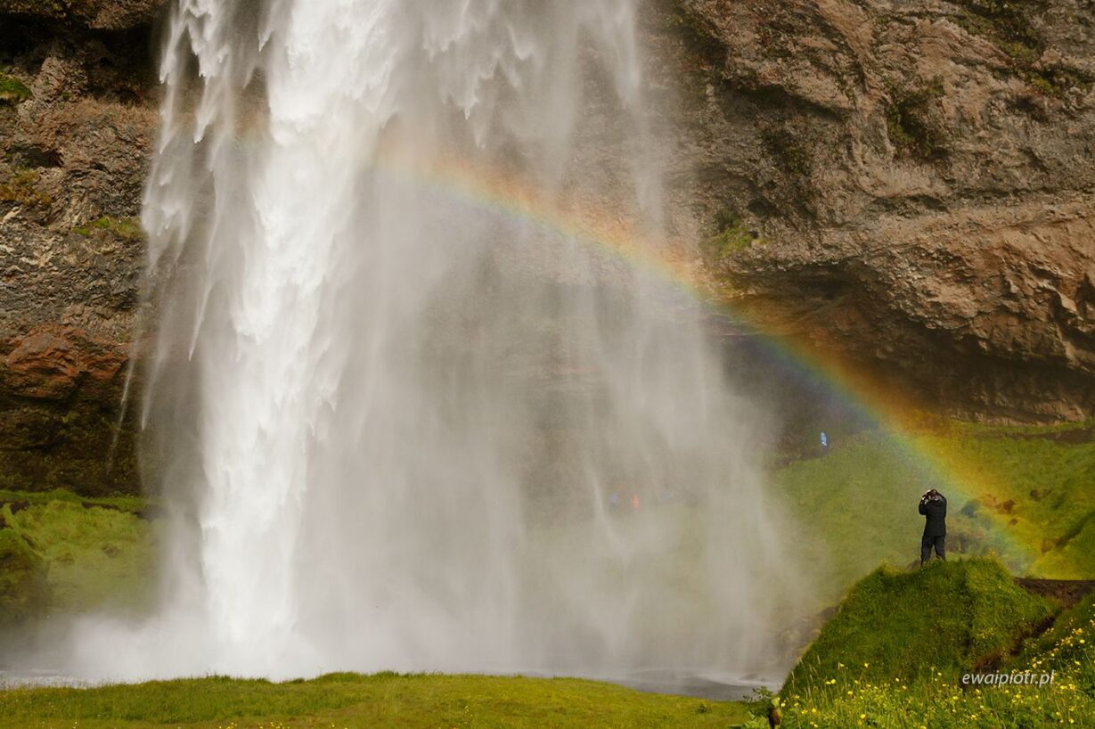 Człowiek, wodospad i tęcza, Seljalandsfoss, Islandia