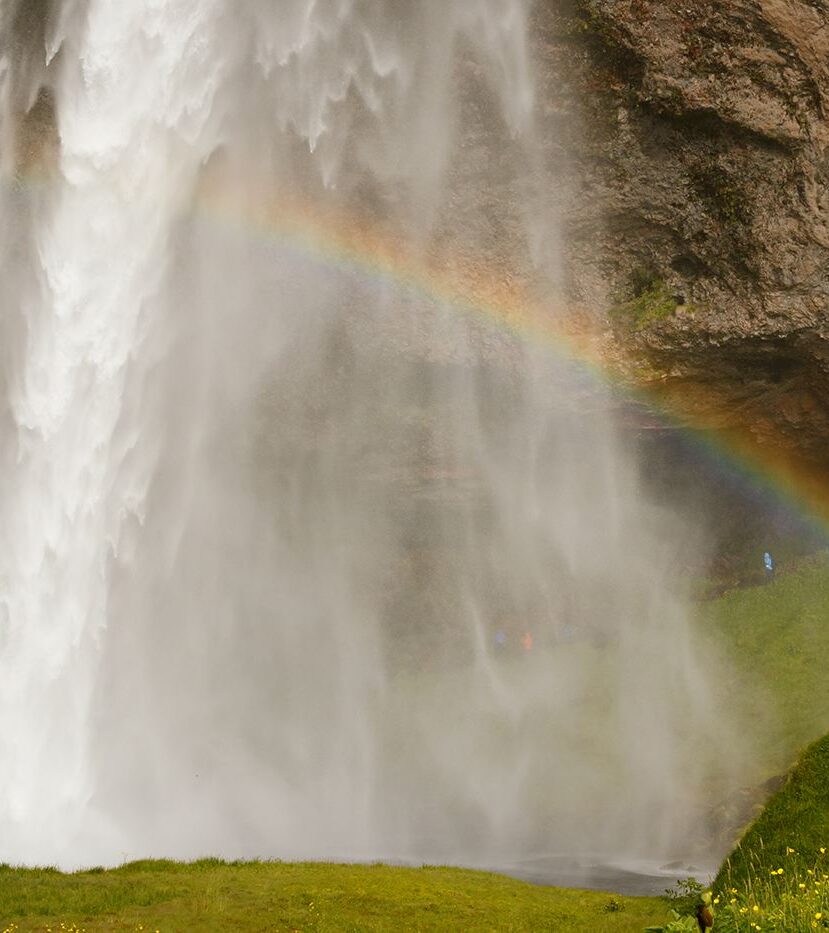 Człowiek, wodospad i tęcza, Seljalandsfoss, Islandia
