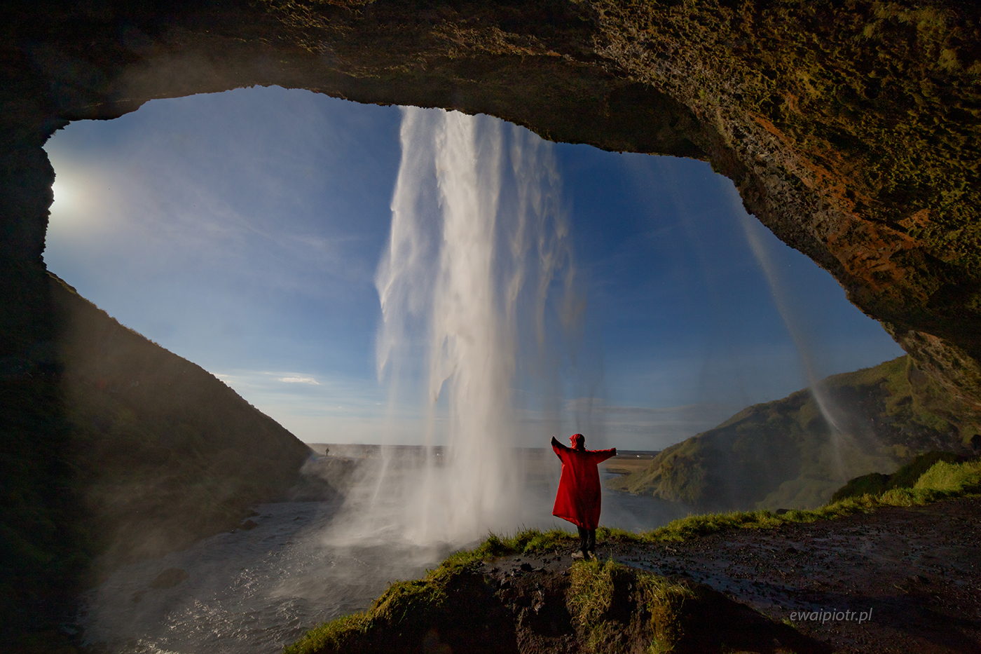 Za wodospadem Seljalandsfoss, Islandia, czerwona peleryna, człowiek za kaskadą wody, fotowyprawa