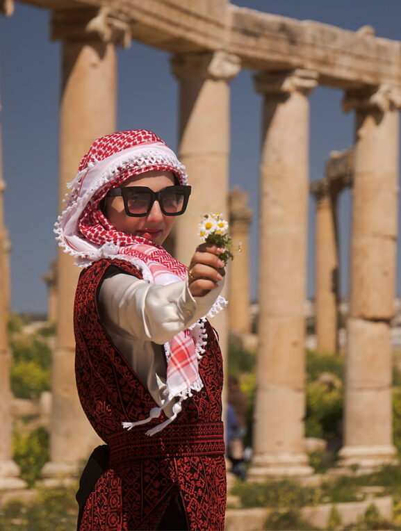 Mais zaprasza do Dżerasz, Jordania, jordańska dziewczyna z kwiatkiem w ruinach starożytnego Dżerasz