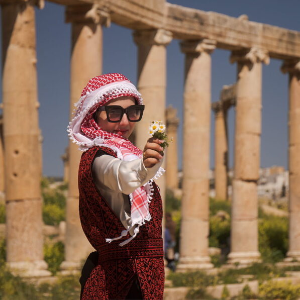 Mais zaprasza do Dżerasz, Jordania, jordańska dziewczyna z kwiatkiem w ruinach starożytnego Dżerasz